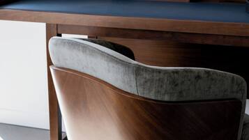 A modern desk with a curved design and a chair with a wooden frame and grey upholstery.