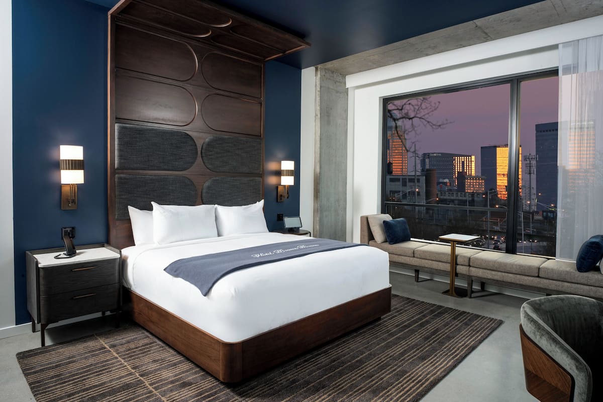 Une chambre d’hôtel moderne dotée d’un grand lit, offrant une vue sur la ville et présentant un design original pour le panneau de tête de lit.