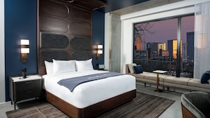 Una habitación de hotel moderna con una cama grande, vistas a la ciudad y un diseño de cabecera único.