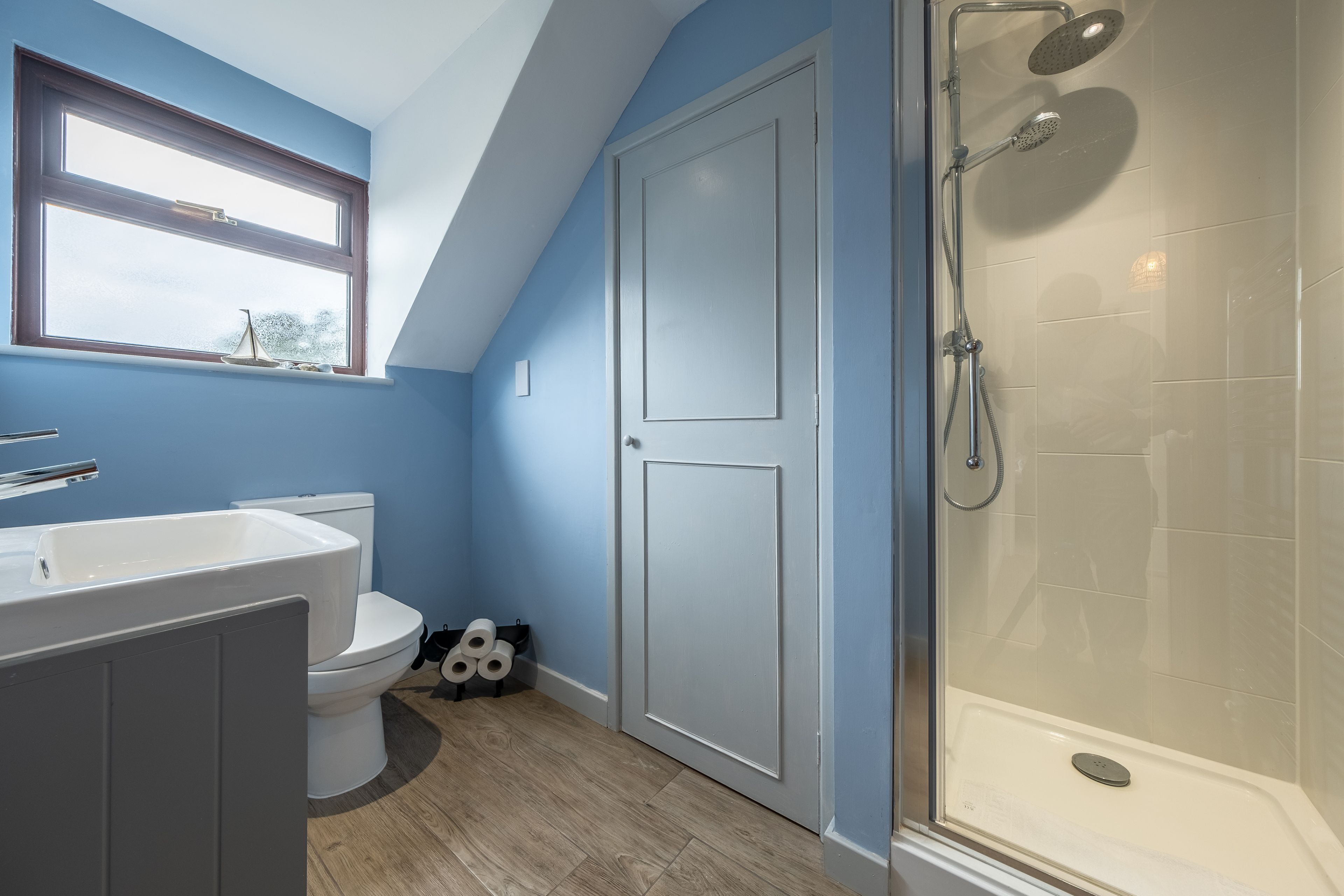 Une salle de bain équipée de toilettes, d’un lavabo, d’une douche et d’une fenêtre.