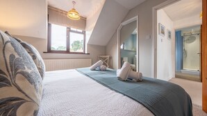 Un dormitorio con cama, ventana, ducha y puerta que da a un baño.