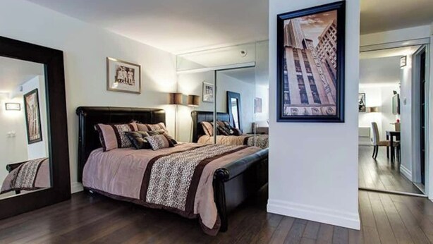 Ein Schlafzimmer mit einem großen Bett, einem Spiegel und einem gerahmten Bild an der Wand.