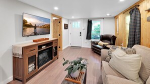 A living room with a flat-screen TV, wooden furniture, a sofa, and a potted plant.