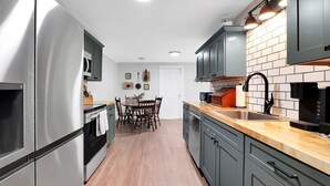 A modern kitchen with stainless steel appliances, dark cabinets, and a wooden countertop.