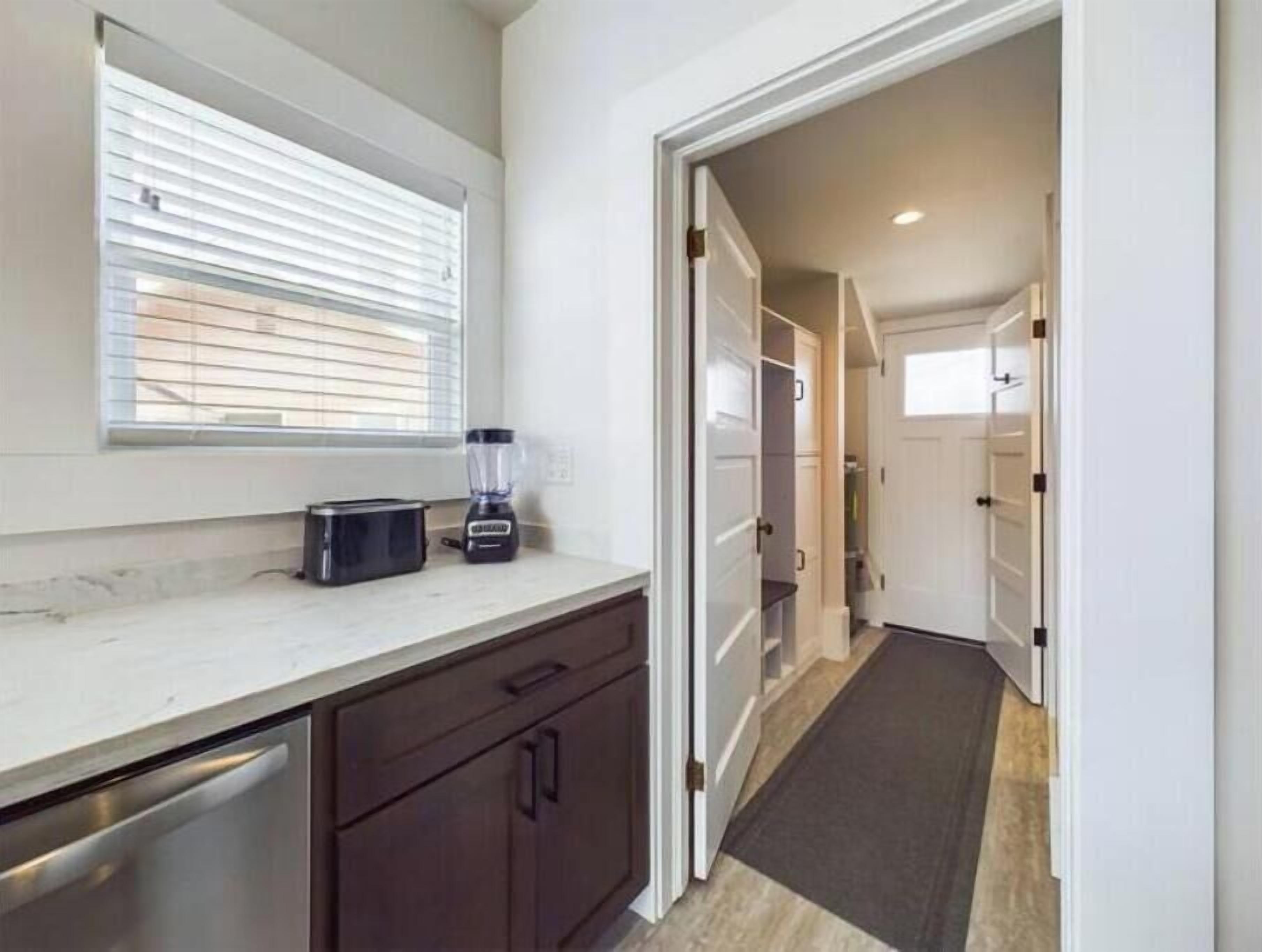 A kitchen with a toaster, blender, and a window with blinds.