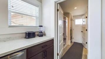 A kitchen with a toaster, blender, and a window with blinds.