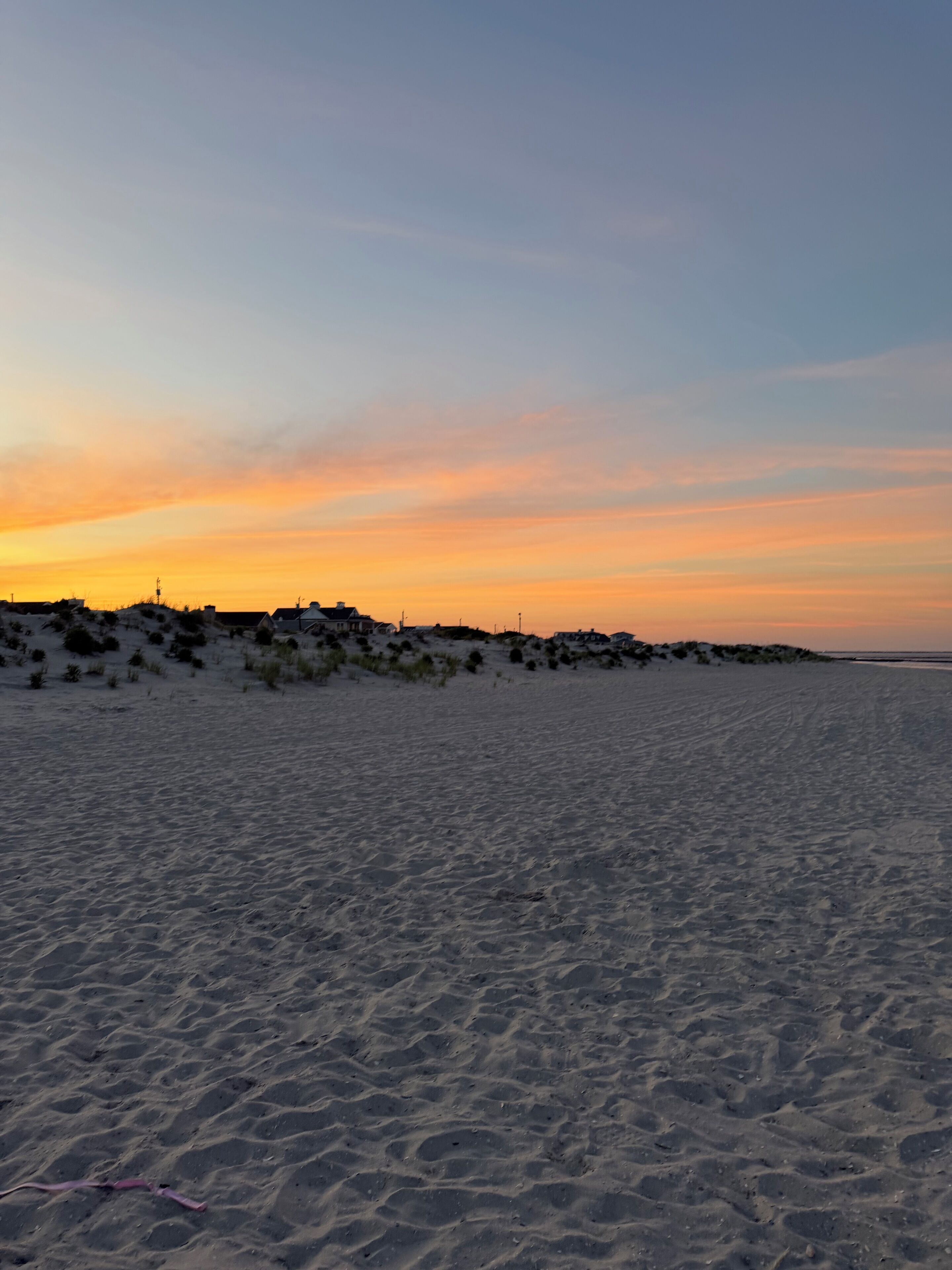 Una platja amb dunes de sorra i un cel de ponent.