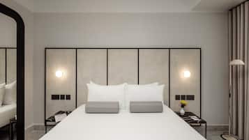 Una habitación de hotel moderna con una cama grande, dos mesitas de noche, una lámpara de pie y un espejo.