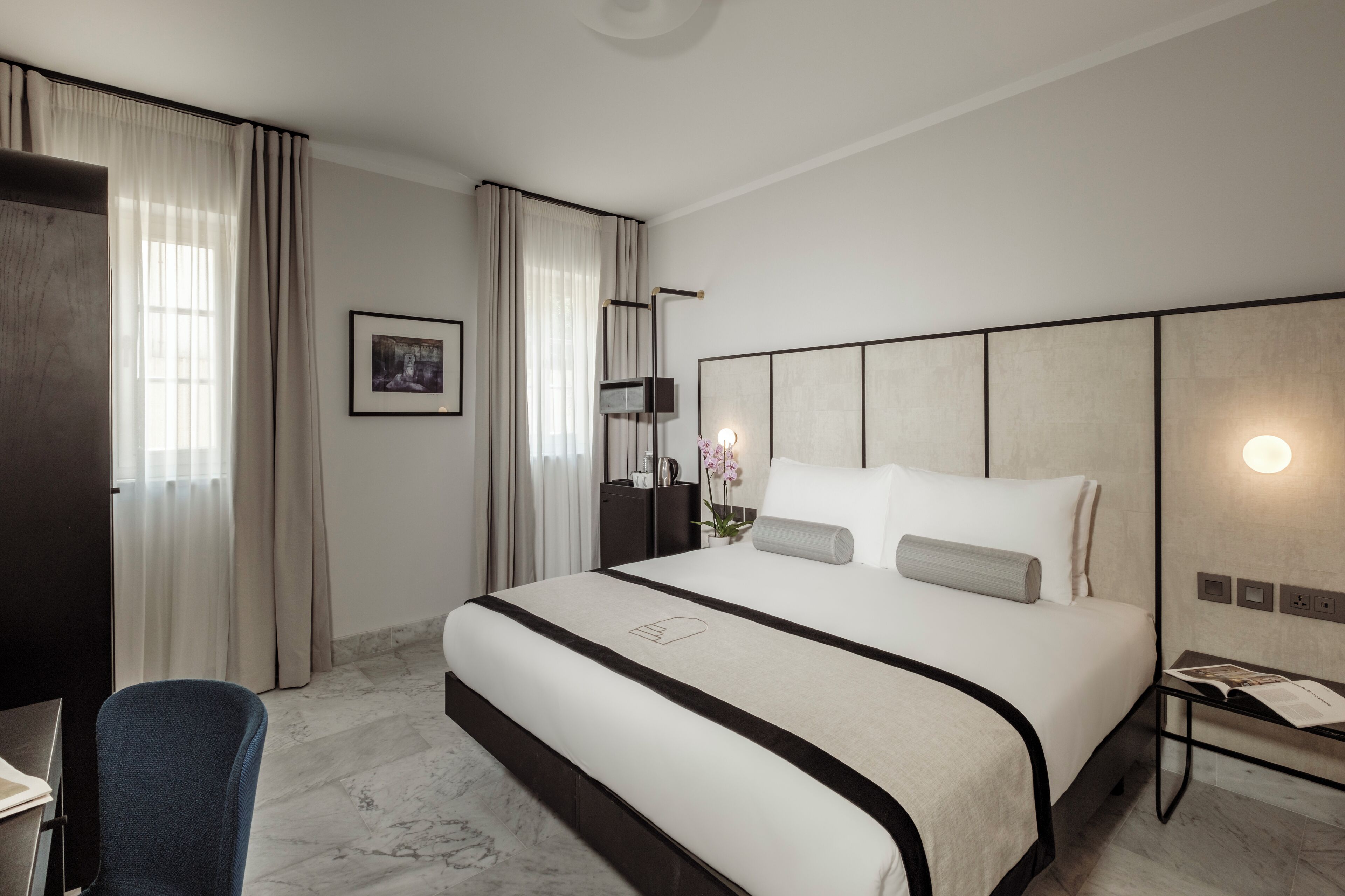 Quarto de hotel moderno com uma cama grande, uma escrivaninha e uma cadeira.