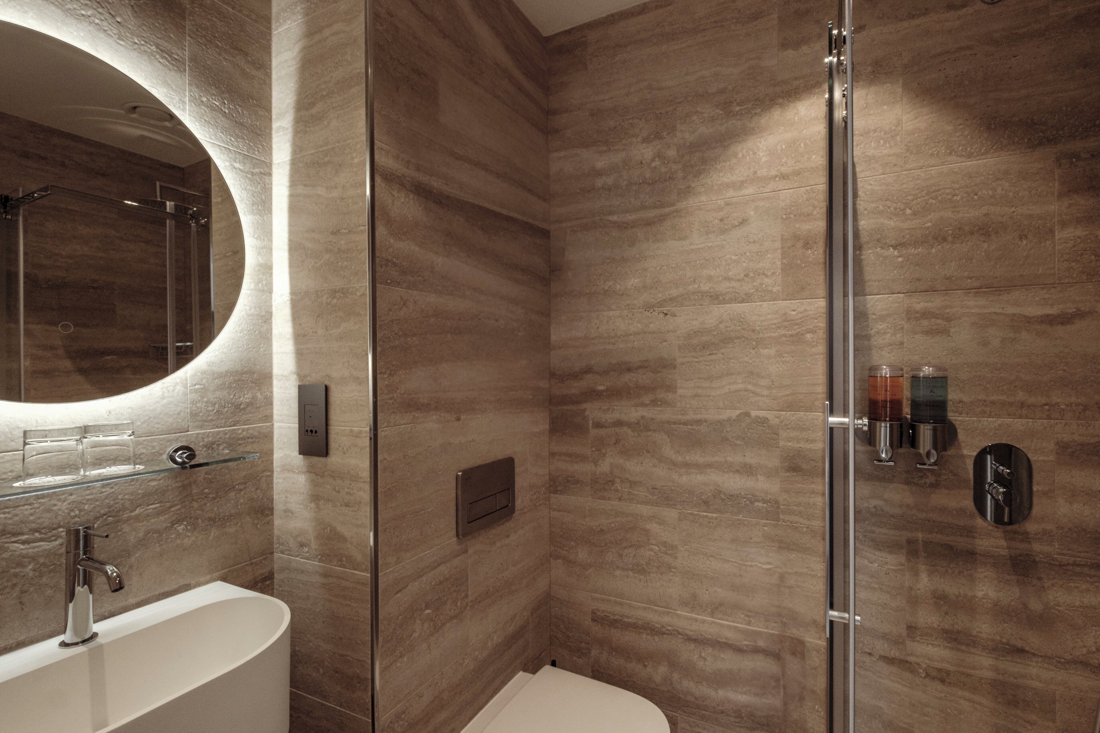 A modern bathroom with a glass-enclosed shower, a freestanding bathtub, and a wall-mounted sink.