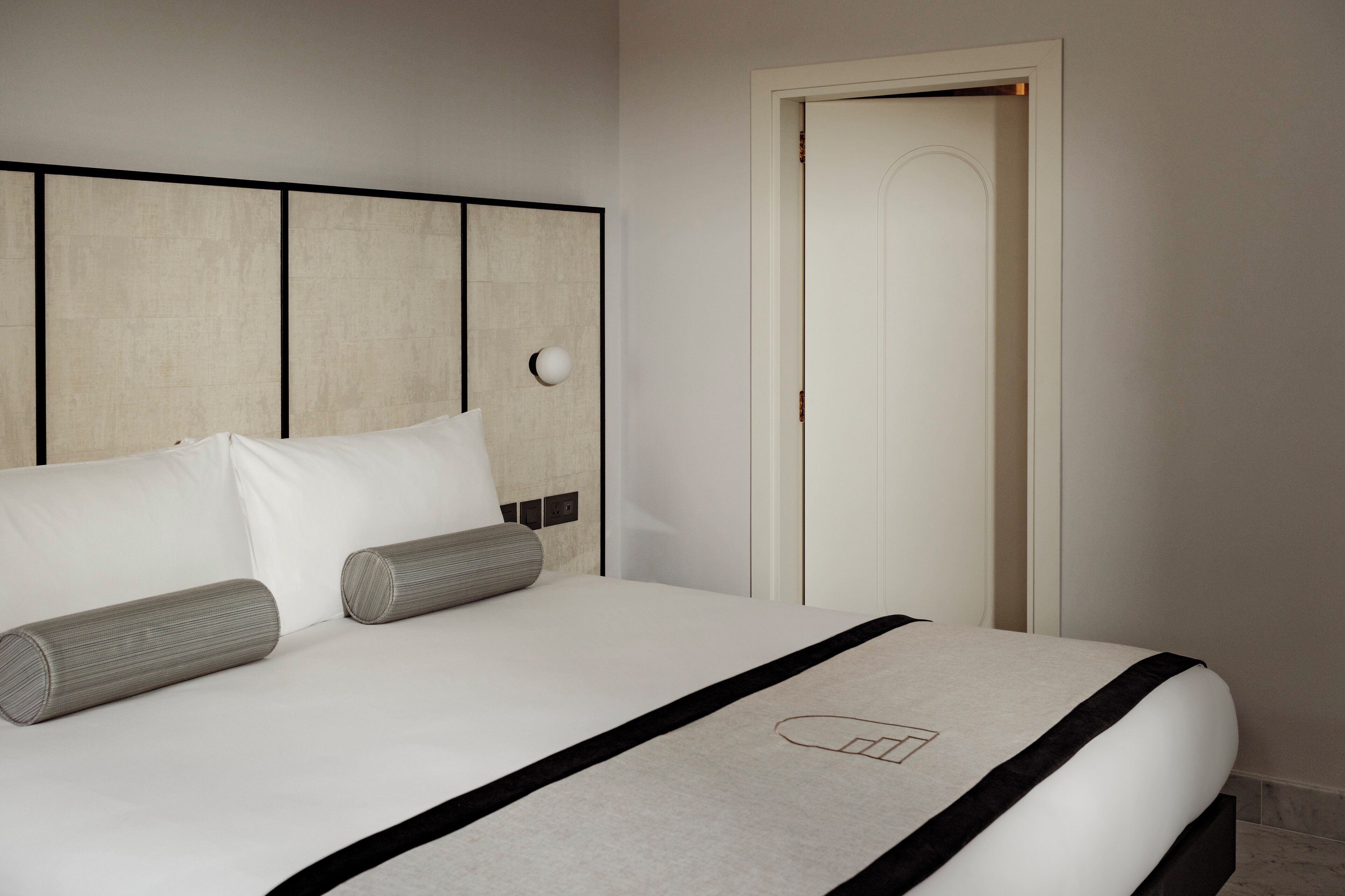Quarto de hotel com cama, cabeceira e porta.