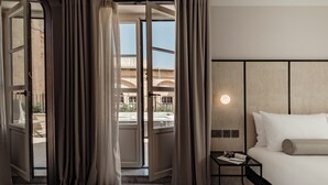 Een hotelkamer met een bed, een nachtkastje en uitzicht.