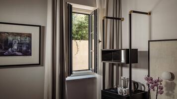 A modern bathroom with a window, a framed artwork, a black cabinet with toiletries, and a mirror.