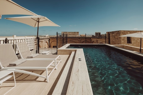 Una piscina al aire libre, sillones reclinables de piscina
