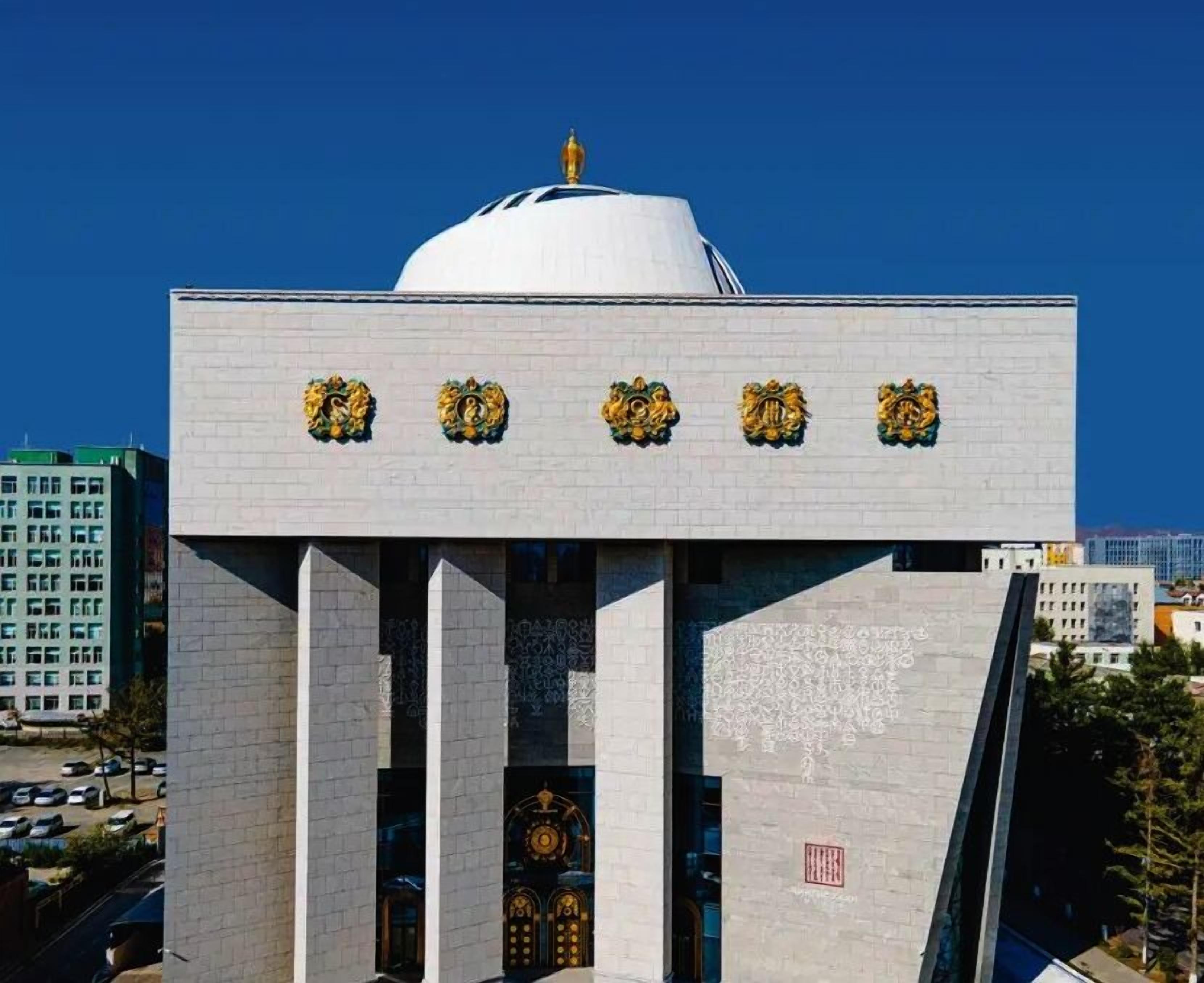 Un edificio con una cúpula blanca y estatuas de leones dorados en la fachada.