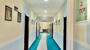 A long hallway with a blue carpet, white walls, and doors on both sides.