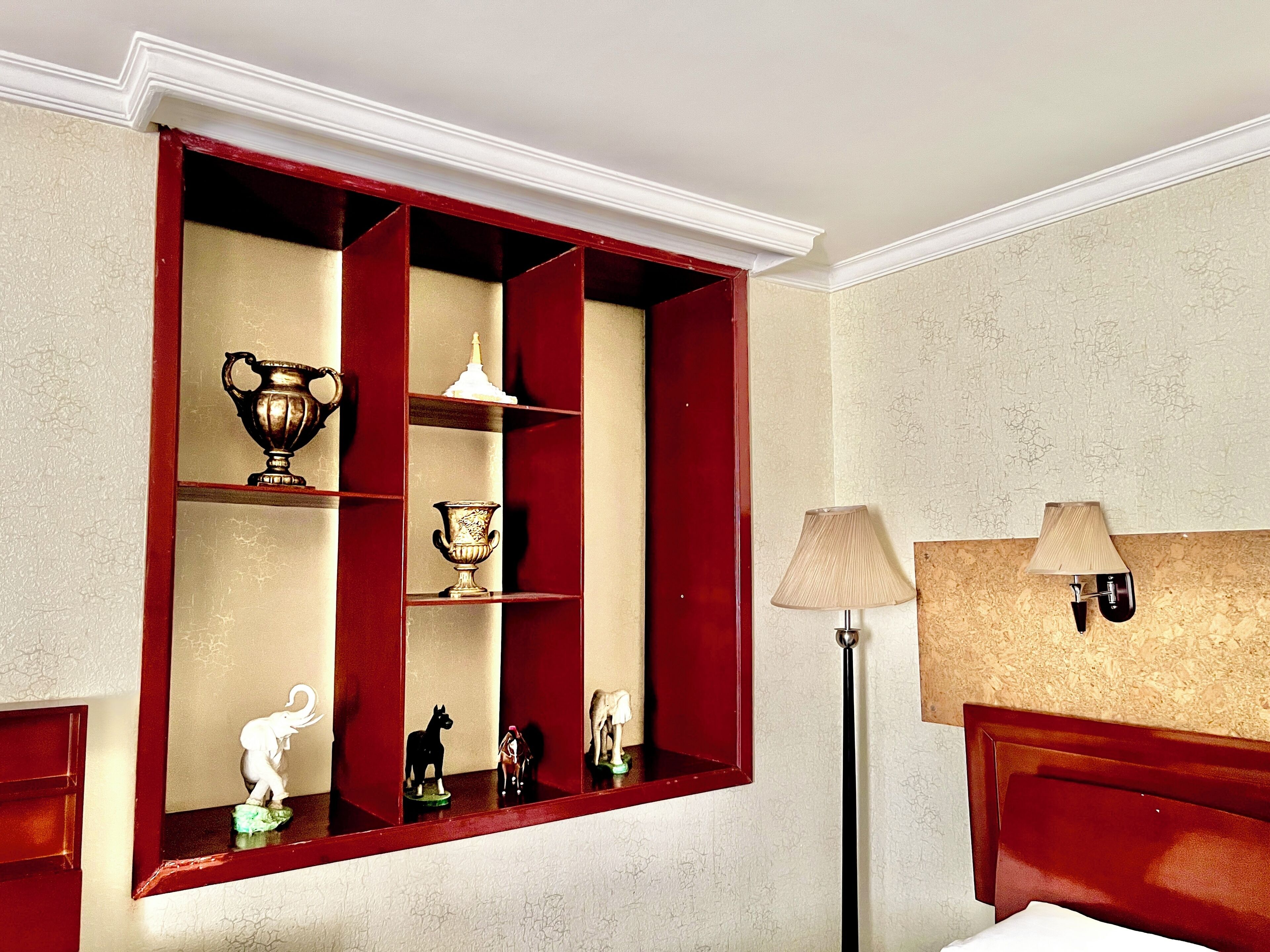 A room with a red-framed window, a lamp, and a bed.