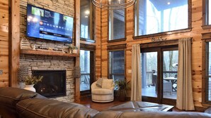 A cozy living room with a fireplace, leather sofa, and a television mounted on the wall.