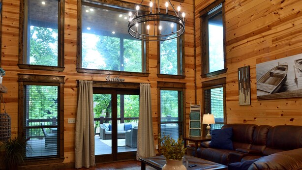 A wooden interior with a leather sofa, a vase with flowers, and a chandelier.