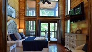 A bedroom with a bed, a dresser, a television, and a ceiling fan.