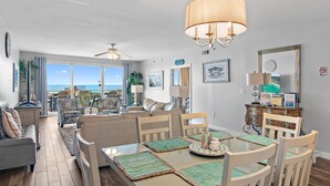 Ein großzügiges Wohnzimmer mit einem großen Esstisch, bequemen Sitzgelegenheiten und Blick auf den Ozean.