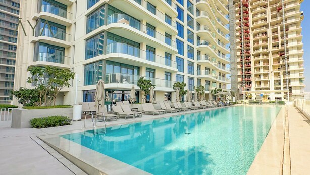 Un hôtel moderne doté d’une piscine sur le toit, de nombreux balcons et offrant une vue dégagée sur le panorama urbain.