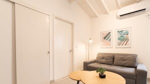 Ein modernes Wohnzimmer mit einem grauen Sofa, einem runden Holztisch und einem gemusterten Teppich.