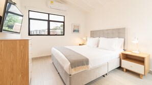 Ein Schlafzimmer mit Bett, Nachttischen, einem Fernseher und einem Fenster mit Blick auf die Stadt.