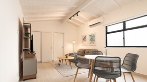 A modern living room with a sofa, dining table, chairs, and a TV. - w Cozy Loft With Fantastic View in El Poblado (Medellín)
