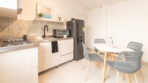 Eine moderne Küche mit Gasherd, integriertem Mikrowellenofen, einem schwarzen Kühlschrank und einem Essbereich mit Tisch und Stühlen.