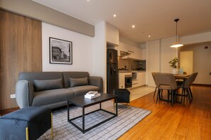 A modern living room with a grey sofa, a coffee table, and a dining area with a table and chairs. - w Glorious 2BR w Amazing Deco in Barranco (Lima)