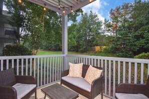 A covered outdoor seating area with wicker furniture and a pergola overhead.