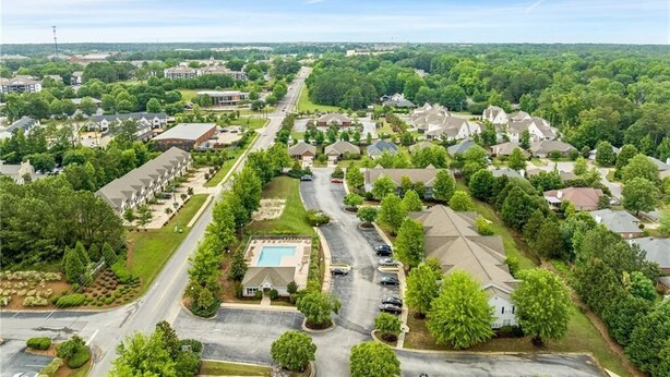 An aerial view of a residential area with houses, roads, and a swimming pool.