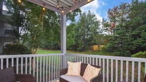 A covered outdoor seating area with wicker furniture and a pergola overhead.
