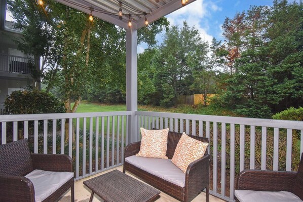 A covered outdoor seating area with wicker furniture and a pergola overhead.