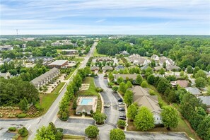 An aerial view of a residential area with houses, roads, and a swimming pool.