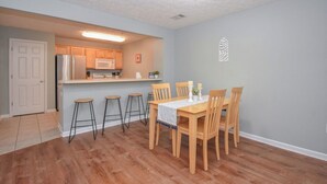 A compact kitchen with a refrigerator, microwave, and bar stools.