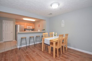 A compact kitchen with a refrigerator, microwave, and bar stools.