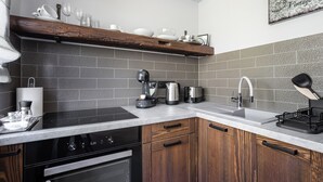 A modern kitchen with a built-in oven, a coffee maker, and a sink. - Radnoti Home (Veszprem)