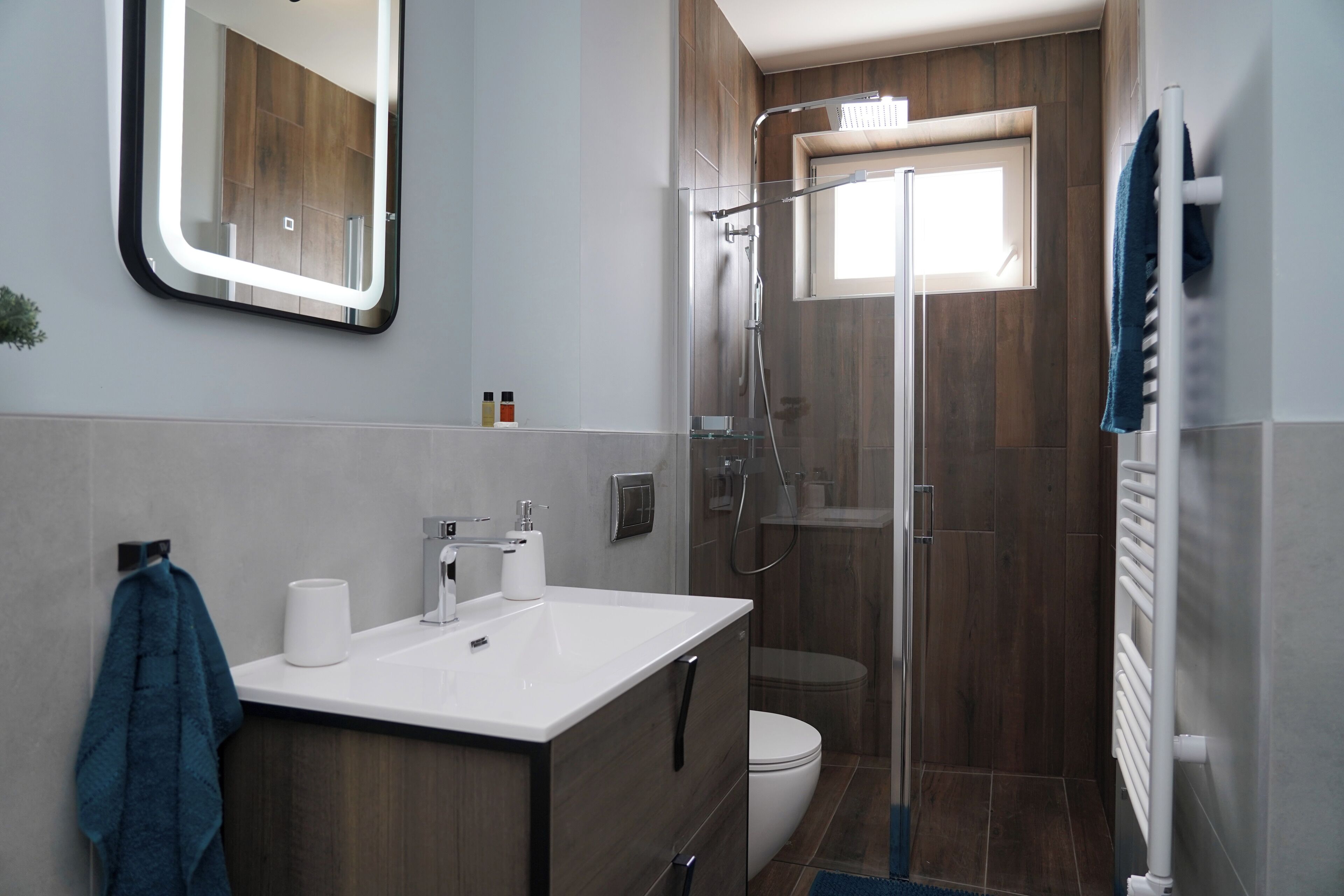 Un bagno moderno con lavabo bianco, specchio e cabina doccia in vetro.