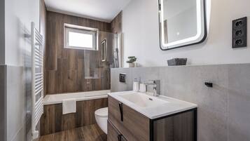 A modern bathroom with a wooden vanity, a bathtub, and a large mirror.