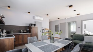 A modern kitchen with a dining area, a sofa, and a view of the living room. - Radnoti Home (Veszprem)