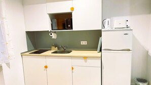A compact kitchen with a sink, a microwave, a coffee maker, and a refrigerator.