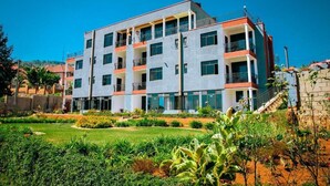 A multi-story building with balconies, a landscaped garden, and a clear blue sky. - Rebero View Apartments (Kigali)