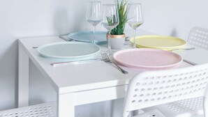 Une table à manger avec des assiettes et des couverts, et un mur décoré de couvertures de livres aux couleurs vives.