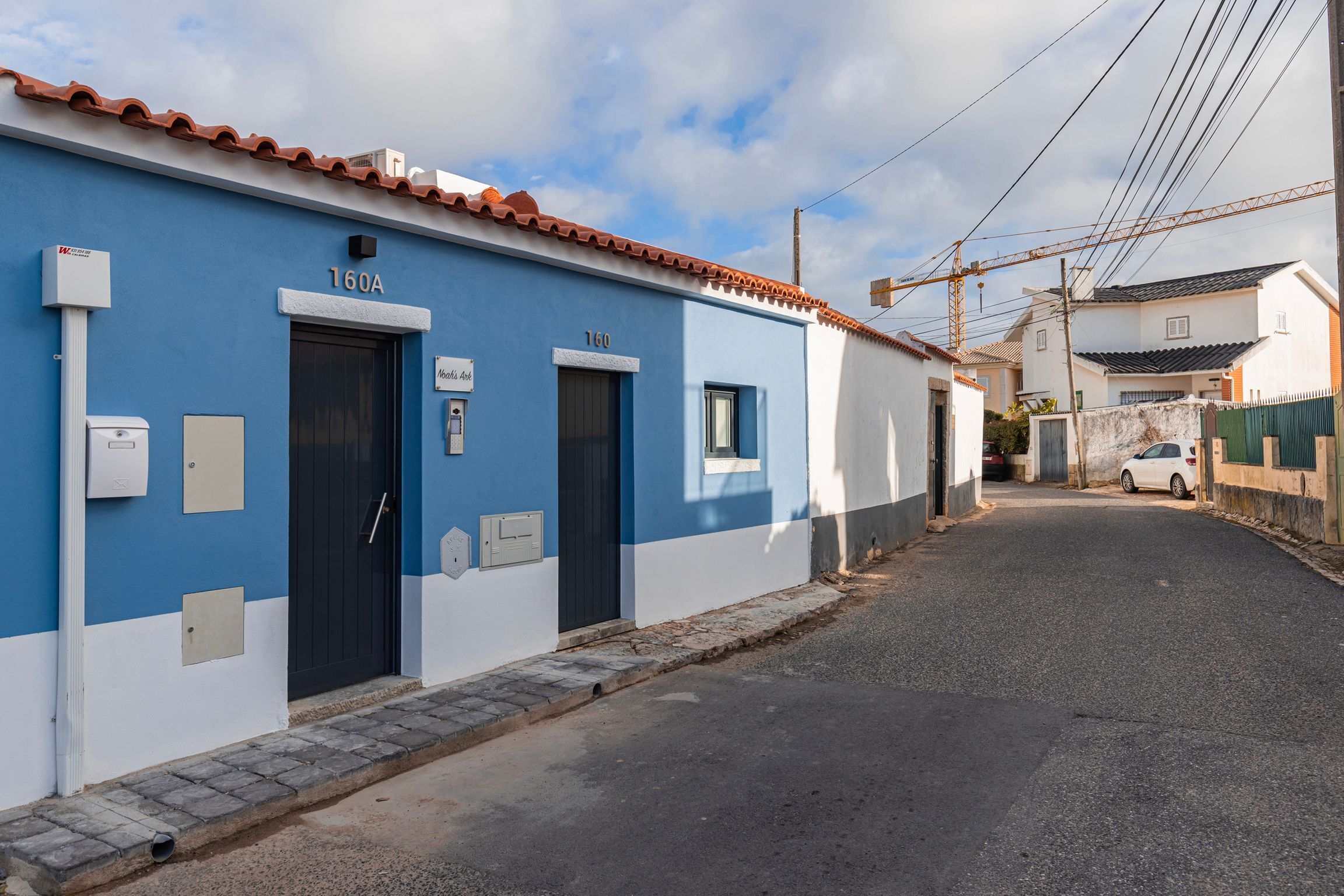 Una calle estrecha con un edificio azul identificado con el número 