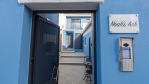 A blue exterior wall with a door labeled "Noah's Ark," a small outdoor seating area, and a security keypad. - Noah's Ark by LovelyStay (Cascais)