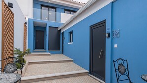 A courtyard with a blue wall, a black door, and a small table with chairs. - Noah's Ark by LovelyStay (Cascais)