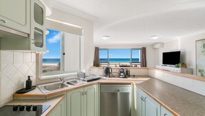 A modern kitchen with a view of the beach, a dishwasher, and a flat-screen TV. - Golden Sea 12 - Absolute Beachfront Bilinga - Min. 3 Night Stays! (Bilinga)