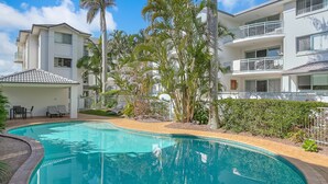 A swimming pool surrounded by palm trees and a covered patio area with lounge chairs. - Golden Sea 12 - Absolute Beachfront Bilinga - Min. 3 Night Stays! (Bilinga)